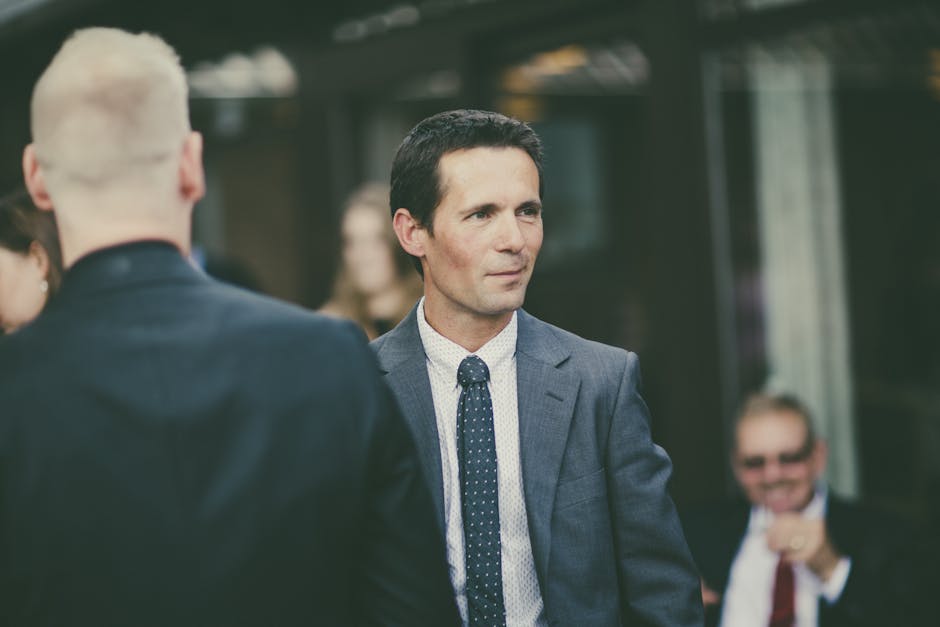 Business professionals in suits attending an outdoor event. Focus on formal attire and networking.
