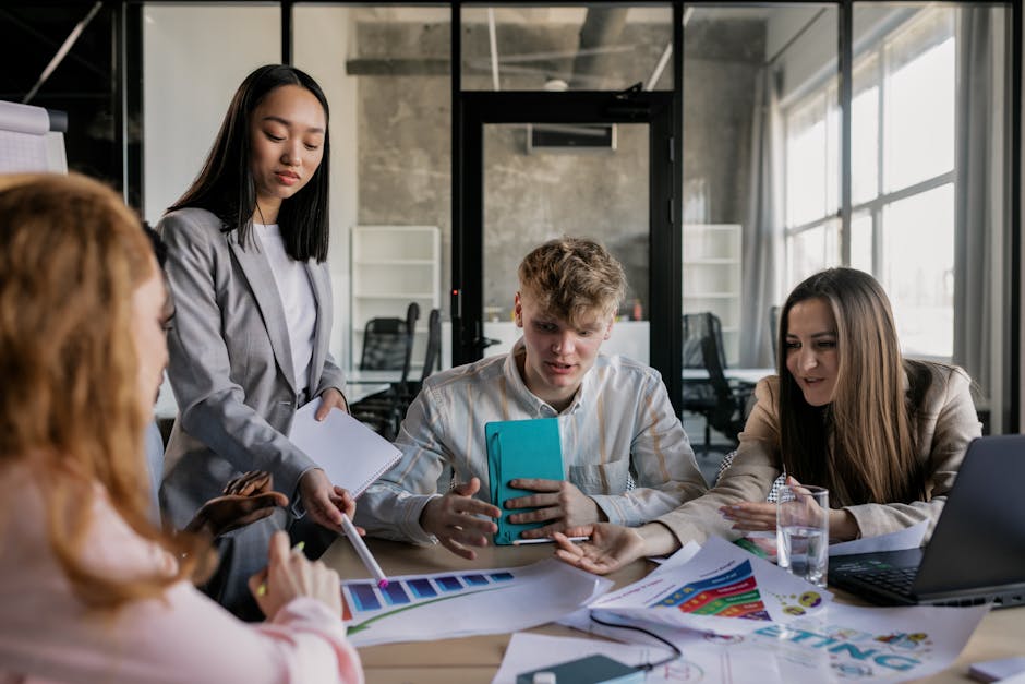referral marketing news April 2026 - A diverse group of colleagues having a lively discussion around a conference table in a modern office.