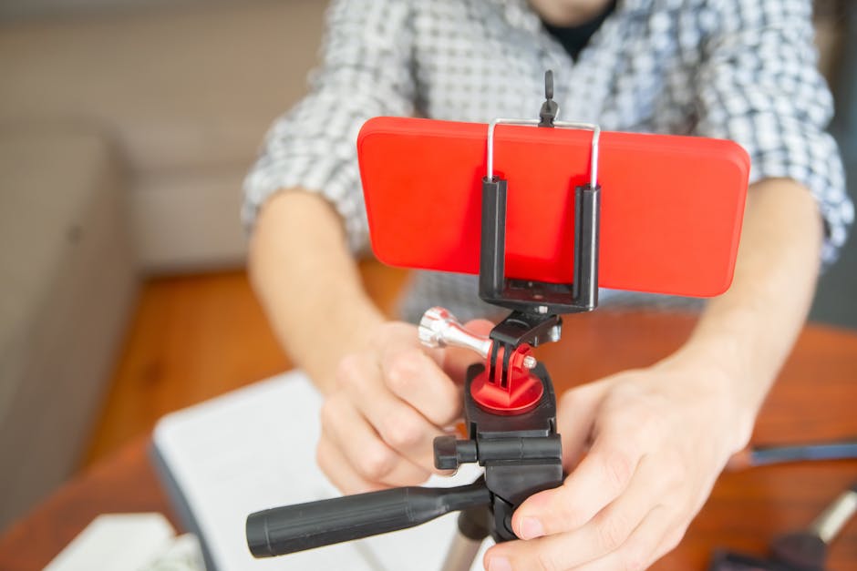 referral marketing news April 2026 - Close-up view of a person setting up a smartphone on a tripod indoors.