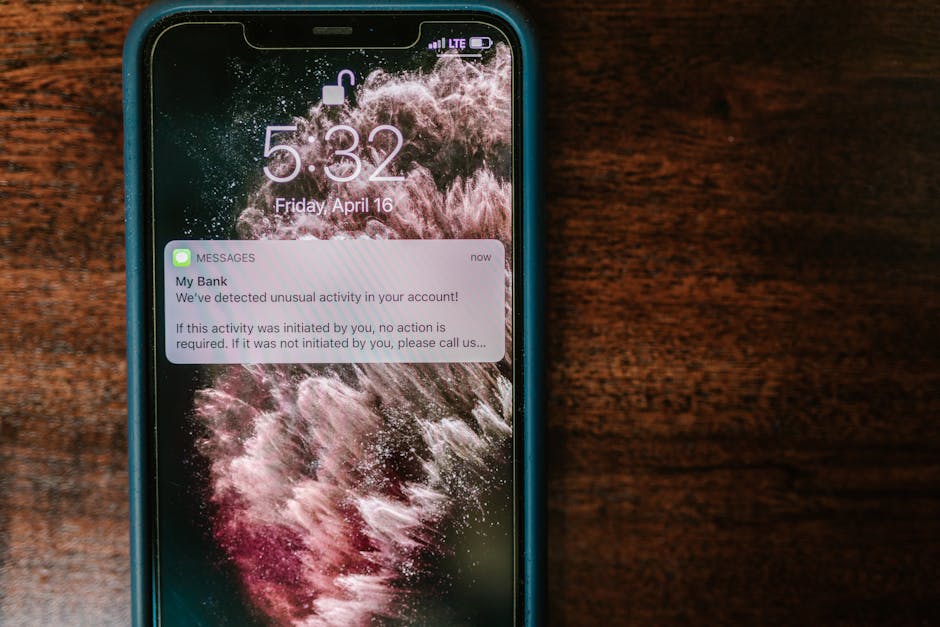 double-sided referral rewards - Close-up of a smartphone displaying a bank alert notification on a wooden table.