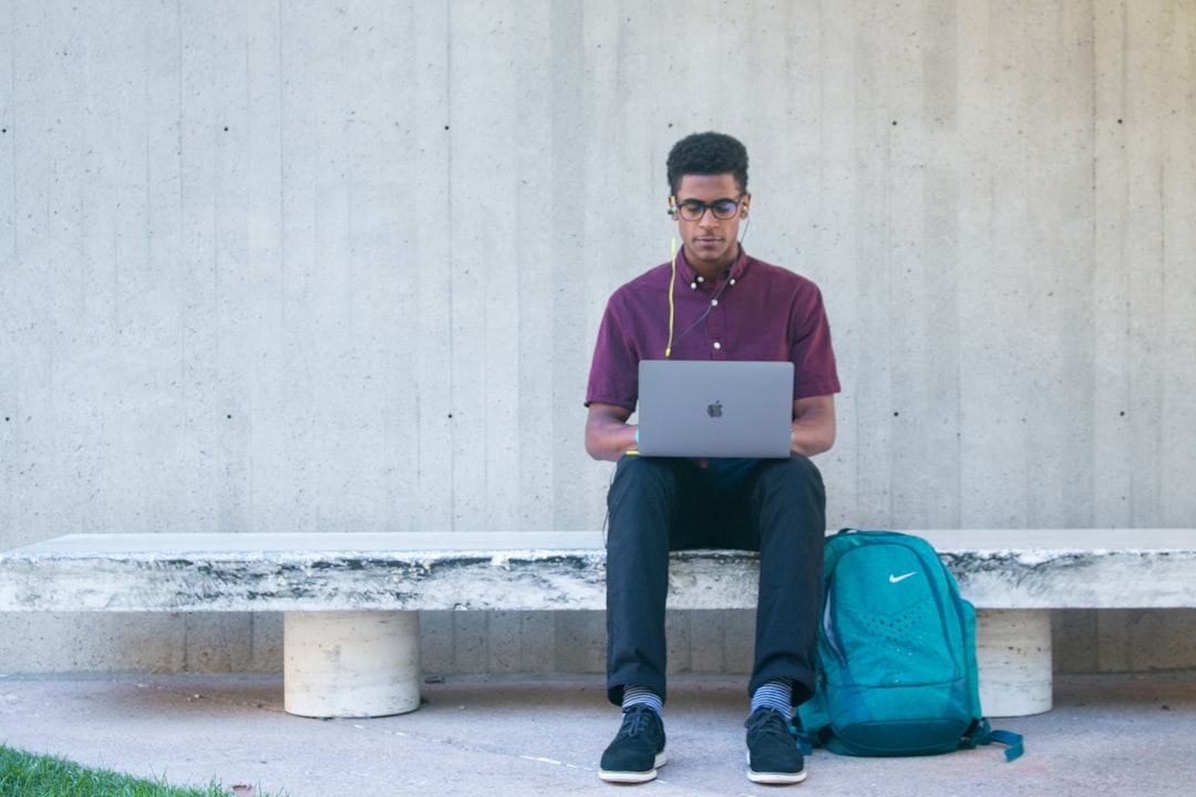 higher education referral marketing - a man sitting on a bench with a laptop