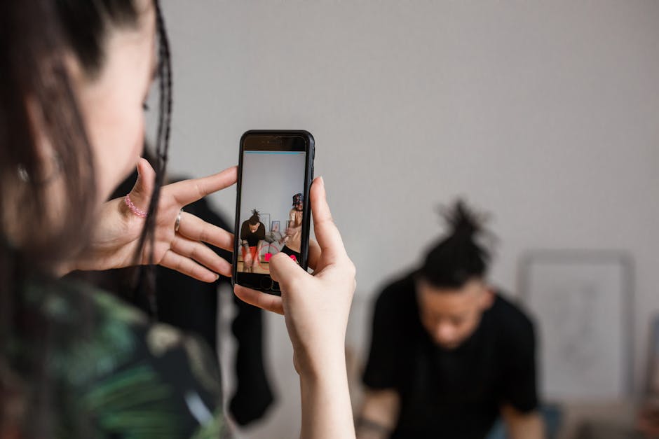 referral marketing news May 2026 - Close-up of a person recording a video with a smartphone indoors, focusing on creative content creation.
