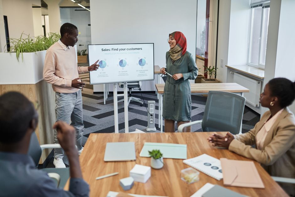 b2b referral program ideas - A diverse team engaging in a business meeting focused on sales strategy with visual aids.