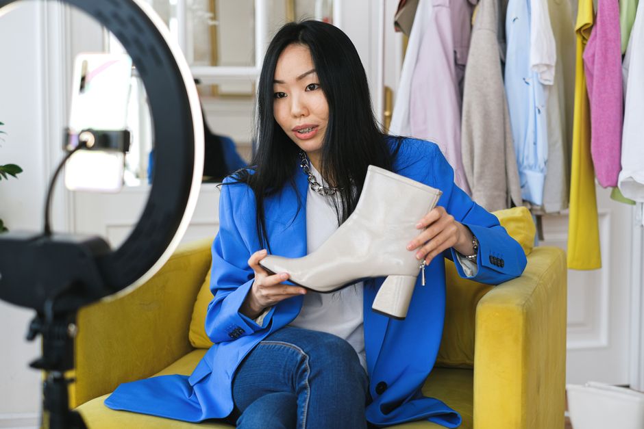 affiliate marketing news - Fashion influencer streaming online reviewing shoes with smartphone and lighting ring.
