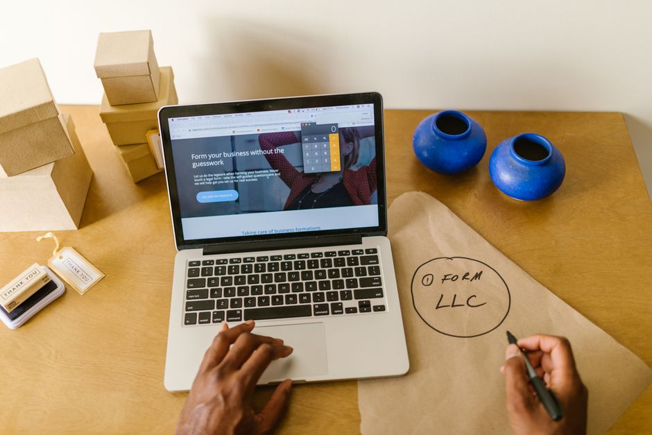 referral marketing news - Workspace with laptop, packaging, and handwritten LLC notes, ideal for a small business startup scene.
